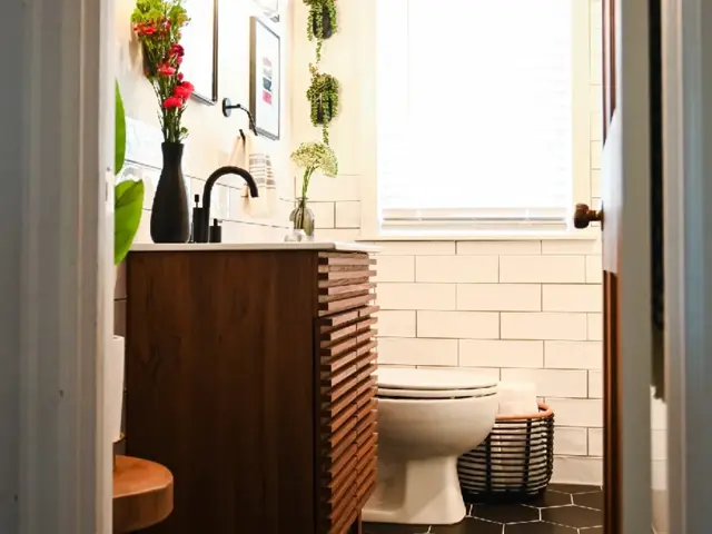 Rebuilt main-floor bathroom with a walnut vanity, white subway tile, and black hexagon floor after water damage restoration by Ungerman