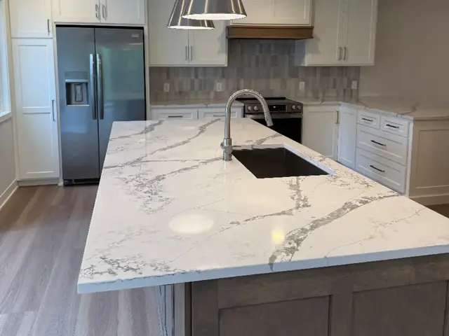 Rebuilt Edina kitchen with white ceiling-height cabinetry, a marble-look quartz island, and a wood hood after fire damage restoration by Ungerman