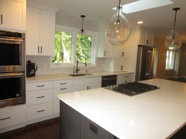Remodeled Edina kitchen with white cabinets, quartz counters, and a large island under a skylight