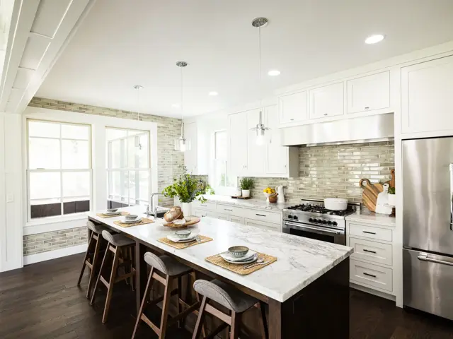 Rebuilt Golden Valley kitchen with white cabinetry, a marble-topped island with wood stools, and new dark hardwood floors after water damage restoration by Ungerman