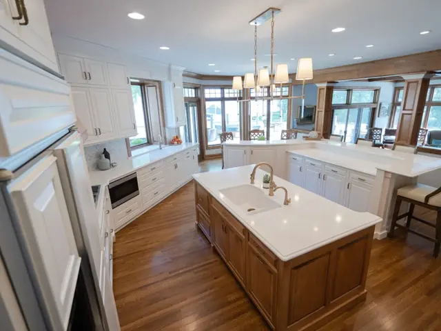 Restored Lake Minnetonka kitchen with white perimeter cabinets, a stained island, and a bay window overlooking the lake after water damage restoration by Ungerman