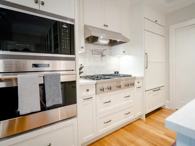 Rebuilt kitchen in a 1920s Minneapolis home with white cabinetry, a gas cooktop, and hardwood floors after fire damage restoration by Ungerman