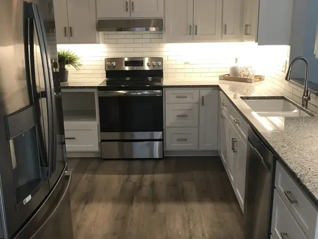 Rebuilt South St. Paul kitchen with white cabinets, granite counters, and subway tile after fire damage restoration by Ungerman
