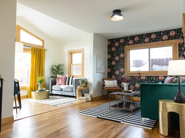 Restored open living room with new hardwood floors, warm white walls, and a floral wallpaper accent wall after storm damage restoration by Ungerman