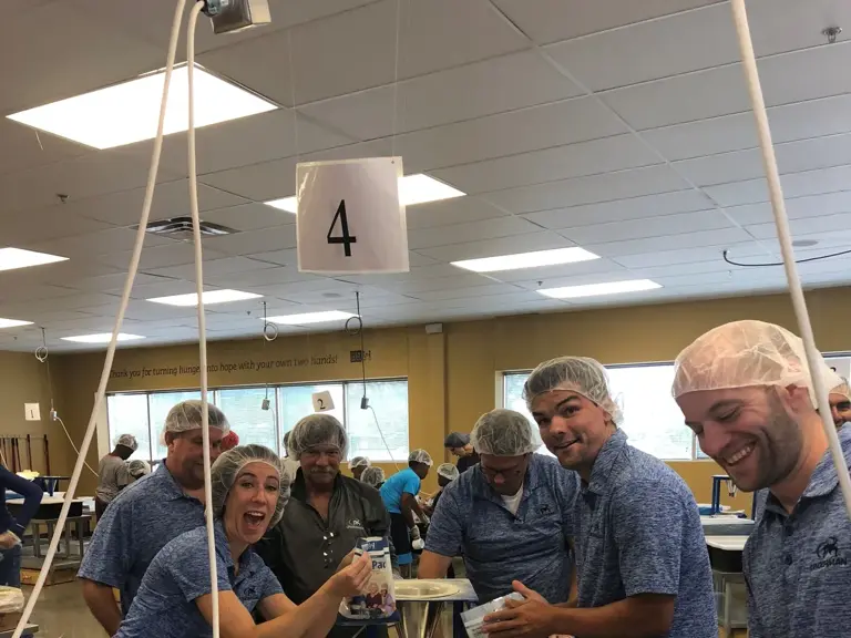 Ungerman team members in hairnets working a meal-packing line at Feed My Starving Children