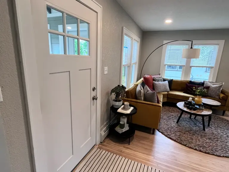 The finished entry of a restored home, looking through the front door to the living room beyond