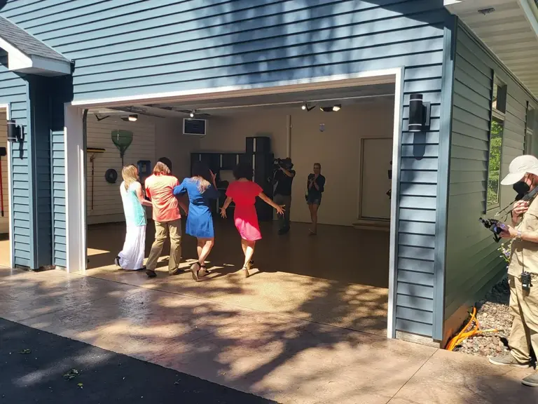 Homeowners walking into a finished garage as a camera operator films the reveal