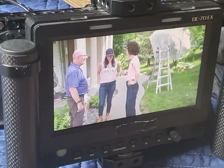 A monitor showing a group gathered outside a house as a scene is filmed