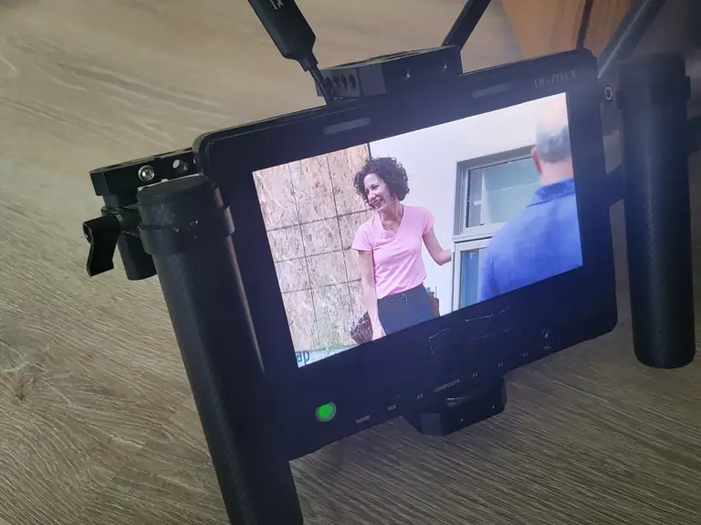 A monitor showing a framed shot of someone speaking beside a window during filming