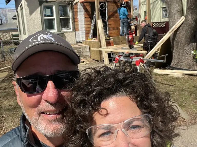 Two Ungerman team members on site in front of a home under reconstruction, new framing visible behind them