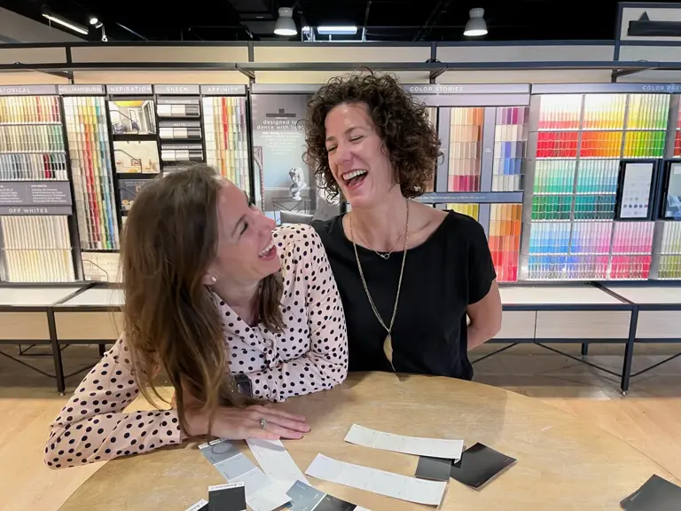 Two people laughing over material samples spread across a table in the selection showroom