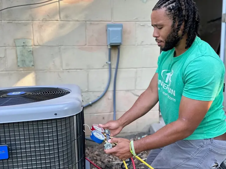 An Ungerman technician taking refrigerant readings with manifold gauges on an outdoor air conditioning condenser