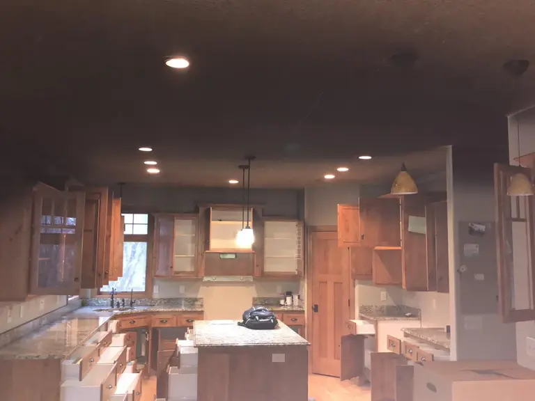 Knotty alder kitchen under a soot-blackened ceiling, cabinets opened for contents cleaning after smoke damage