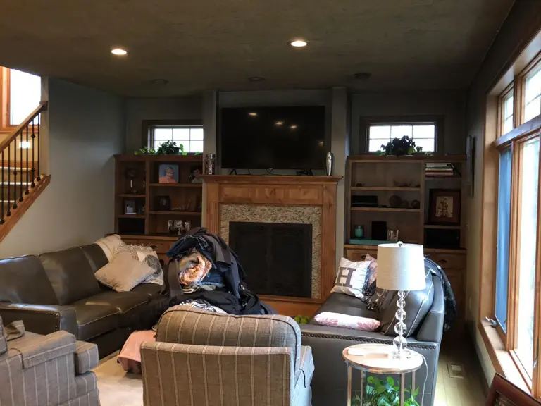 Living room with dark wood built-ins and fireplace surround under a smoke-stained ceiling before fire restoration
