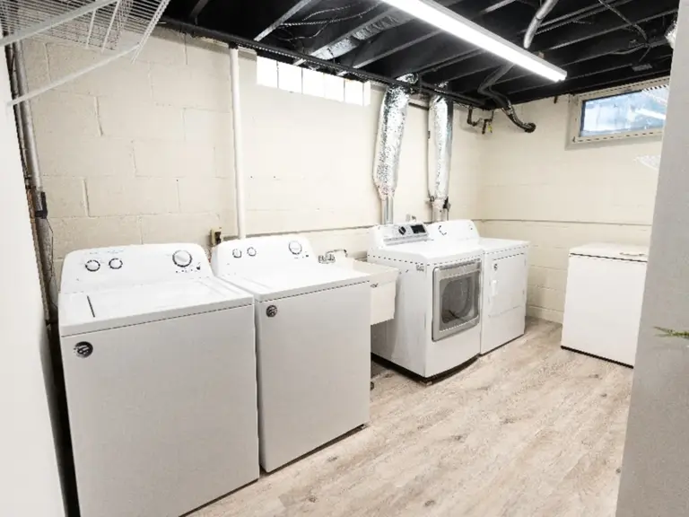 The same laundry room refinished with painted block, new plank flooring, and linear lighting