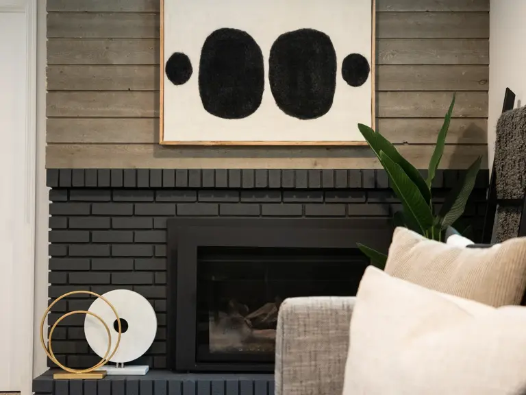 The same fireplace with brick painted black and a shiplap surround after the basement remodel