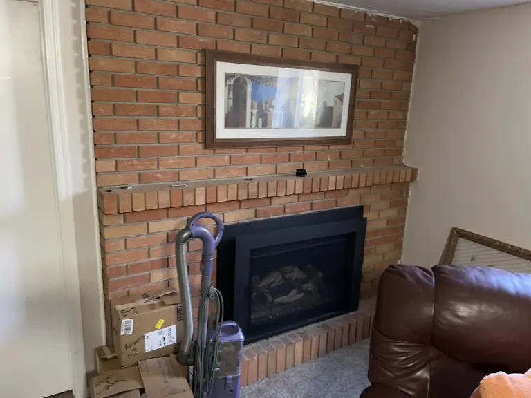 Original red brick basement fireplace surrounded by stored boxes before the basement remodel