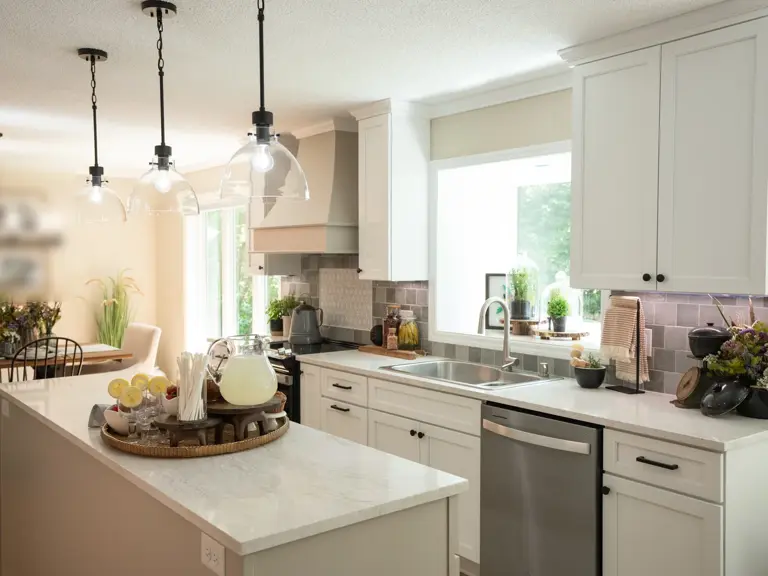 The same kitchen rebuilt with white cabinetry, a marble-look quartz island, a range hood, and grey tile, opened toward the dining area