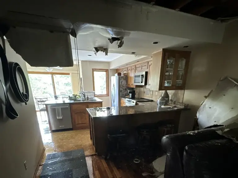 Dark peninsula with granite counter and a collapsed ceiling above, seen from the living area before restoration