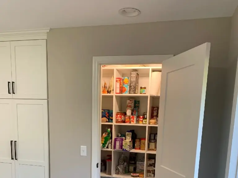The same location rebuilt as a walk-in pantry with open shelving behind a white door