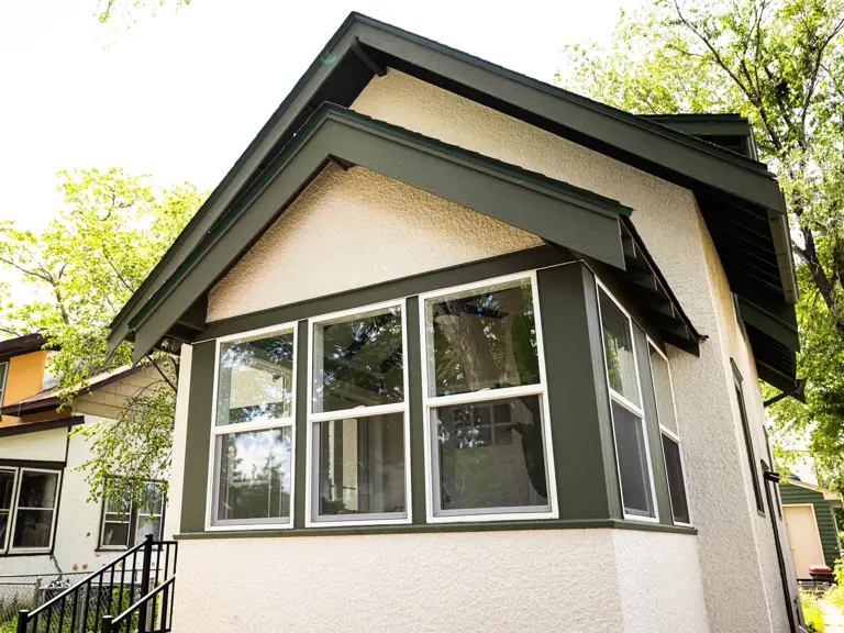 Restored stucco exterior with new trim, bay window, and replacement windows after fire restoration