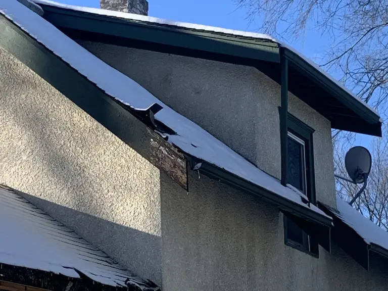 Fire-damaged stucco exterior with burned soffit, scorched fascia, and smoke staining after a house fire