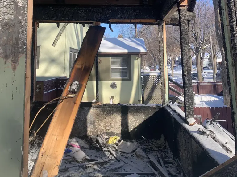 Front porch destroyed by fire, showing charred framing and debris where the fire started