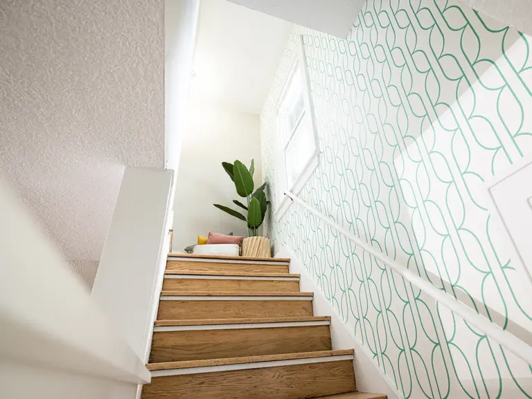 Restored stairwell with refinished wood treads and patterned wallpaper after fire restoration