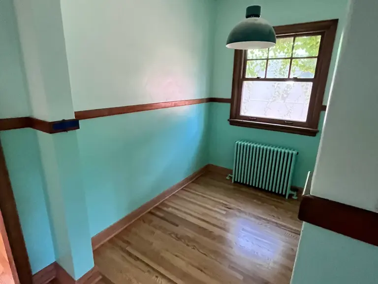 The same breakfast nook cleared and refinished, with new-looking hardwood floors and a restored column radiator revealed beneath the window