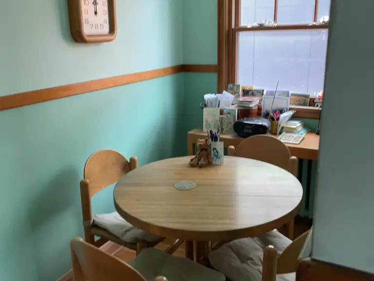 Teal breakfast nook with a round table and two-tone walls, its radiator hidden behind a cluttered desk before frozen pipe restoration