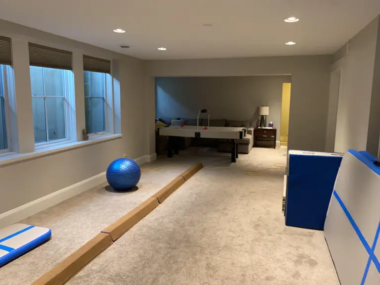 Golden Valley basement before the remodel — a carpeted open space used for play and exercise, with high windows along the left wall