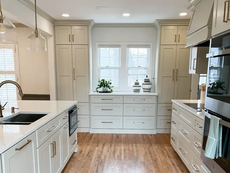 The same window wall rebuilt with full-height shaker pantry cabinets either side and a deep bank of drawers under a quartz counter