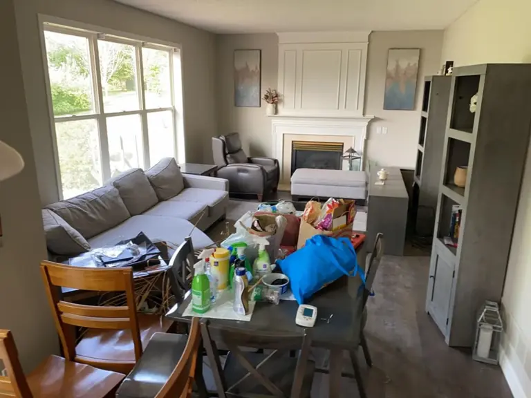 Living room with a white fireplace and household contents piled on the table during cleaning after the lightning-strike fire