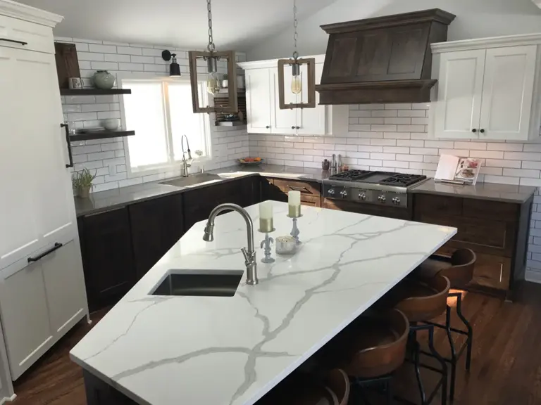 The finished kitchen with a quartz island, dark stained cabinetry, a range wall, and subway tile