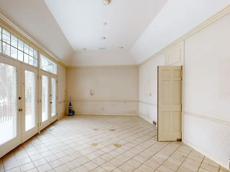 Empty dining room with a vaulted ceiling, a wall of French doors, and dated tile flooring before the remodel