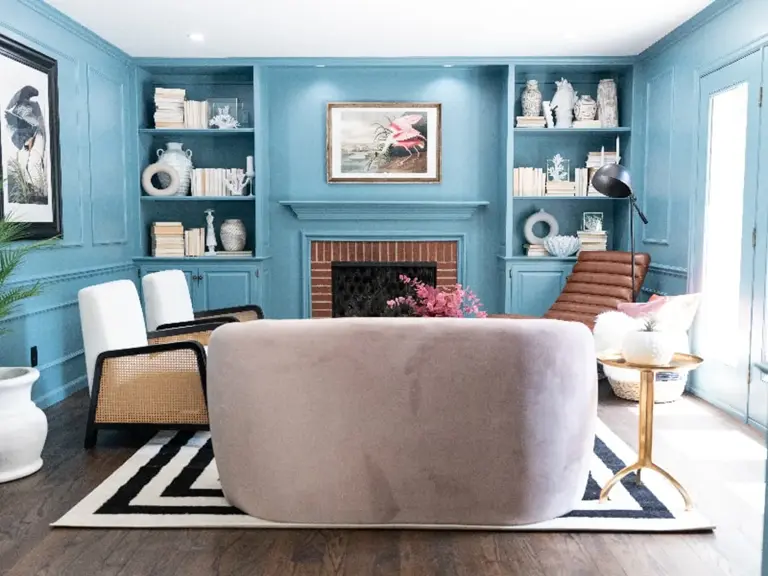 The same room remodeled with blue-painted walls and built-ins framing the original brick fireplace, with the French doors restored on the right