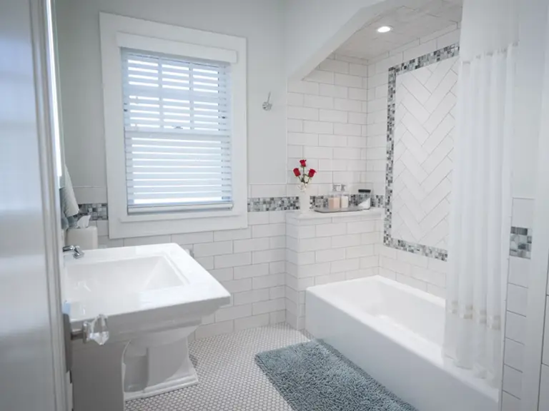 The same bathroom rebuilt with white subway tile, a glass mosaic border, and a hexagon tile floor