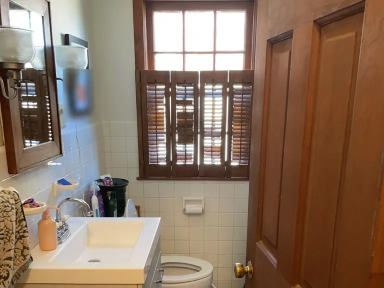 Original bathroom with an oak vanity, a cultured-marble sink, small square wall tile, and wood window shutters before the remodel