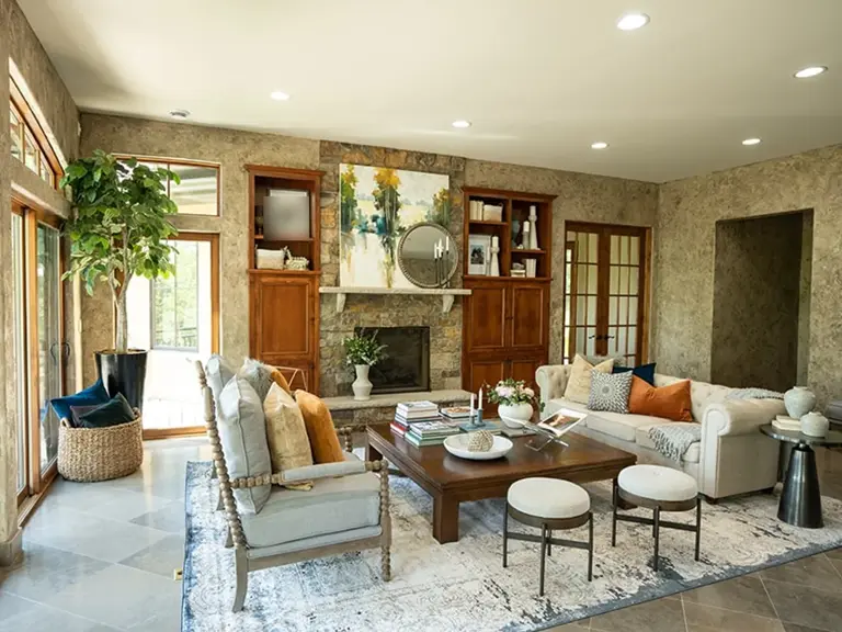 The same great room after restoration, the stone fireplace and built-ins kept but styled bright with new furnishings, artwork, and light flooring