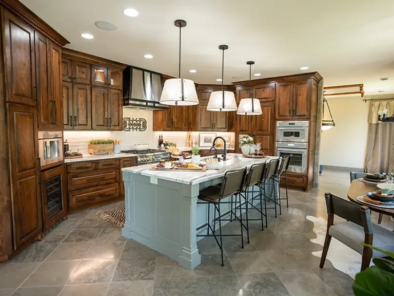The same kitchen opened up after restoration, the peninsula gone and replaced by a grey island with quartz counters, cherry cabinets, and a metal hood