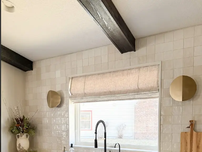 The same window wall rebuilt with a farmhouse sink, stone counters, and hand-glazed tile after restoration