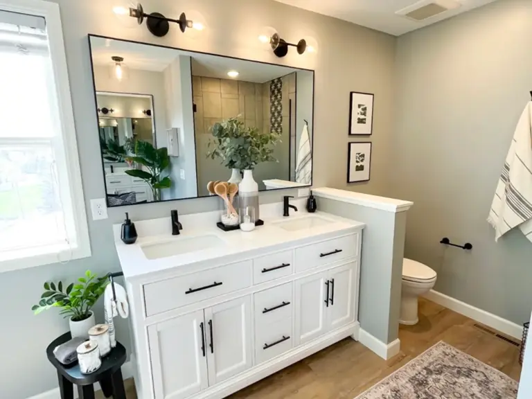 The same wall rebuilt with a white double vanity, black framed mirror, and sconce lighting