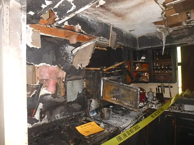 Charred cabinetry and collapsed ceiling material along the range wall after the fire