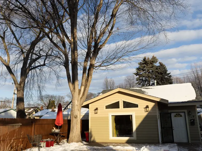 The same rear elevation after storm damage restoration, with a rebuilt roof, new siding, and a peaked transom window set into the gable