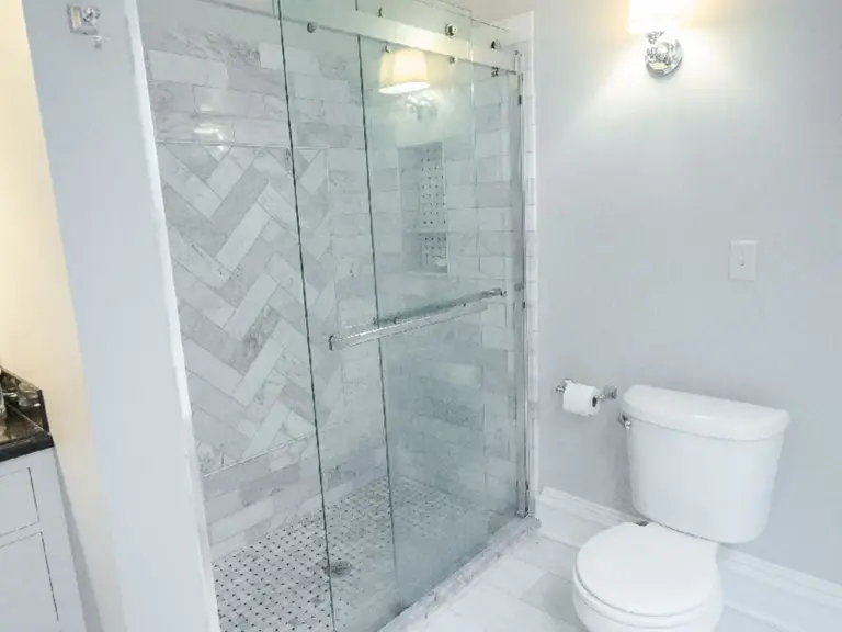 The same bathroom rebuilt with a marble herringbone walk-in shower and mosaic tile floor