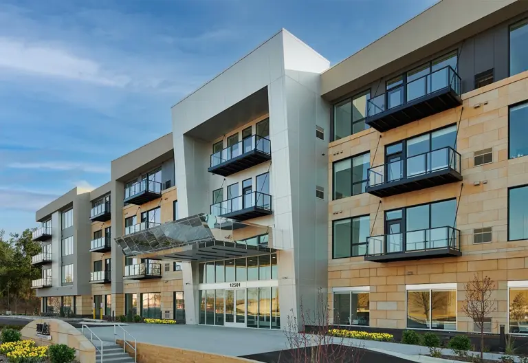 Exterior of a modern four-story Twin Cities apartment building with balconies and a glass entry canopy