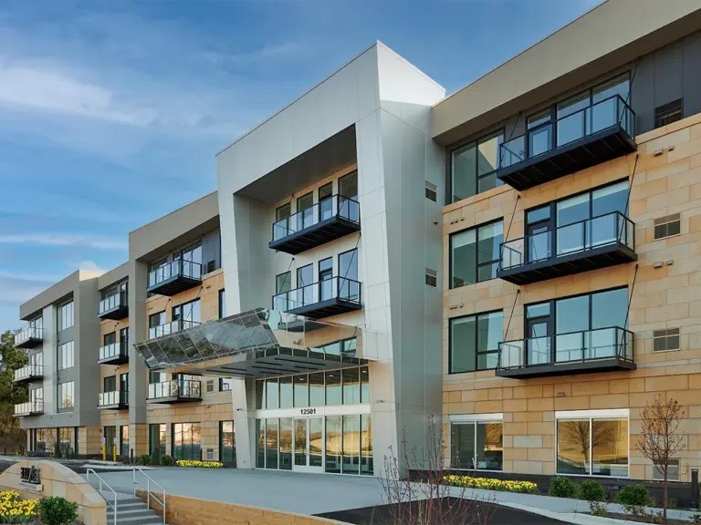 Exterior of a modern four-story Twin Cities apartment building with balconies and a glass entry canopy