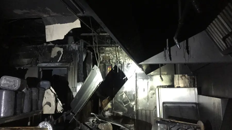 A fire-damaged commercial interior with charred debris and collapsed ceiling material