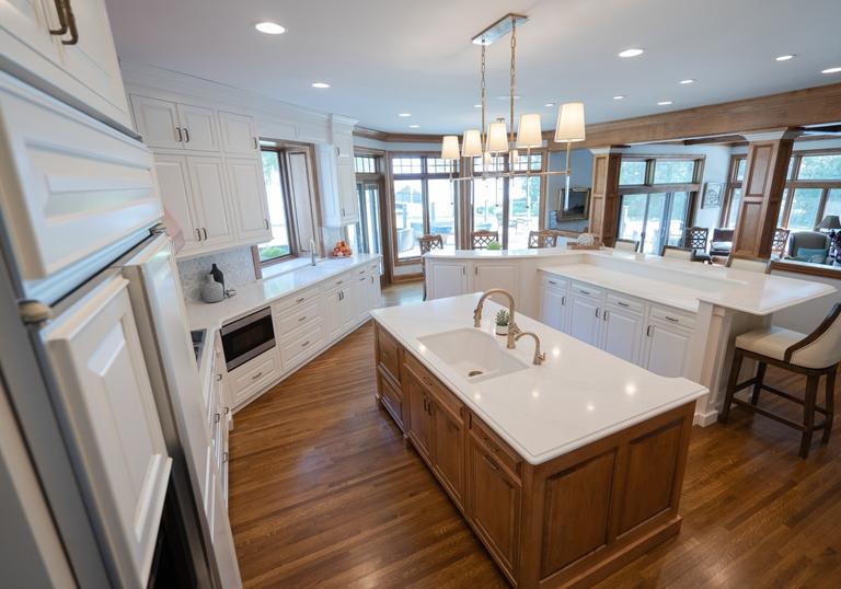 Completed kitchen repair with white cabinets, pendant lights, and a central island