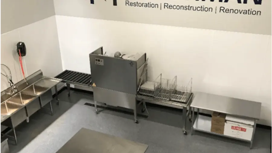 The Ungerman contents cleaning room with stainless steel work tables beneath the company wall sign